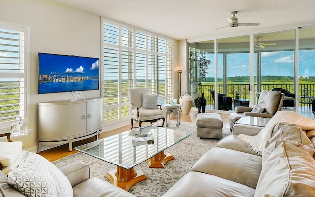 living room with a wall of windows, wood-type flooring, and ceiling fan