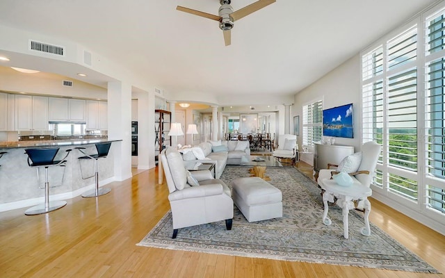 living area with a ceiling fan, light wood finished floors, and visible vents