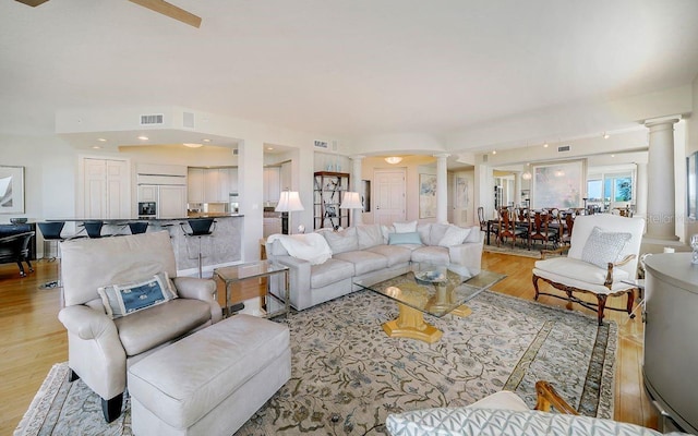 living room featuring light wood-style floors, decorative columns, and visible vents