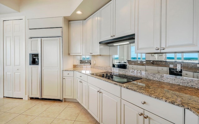 kitchen featuring paneled fridge, light tile patterned floors, black electric stovetop, under cabinet range hood, and recessed lighting