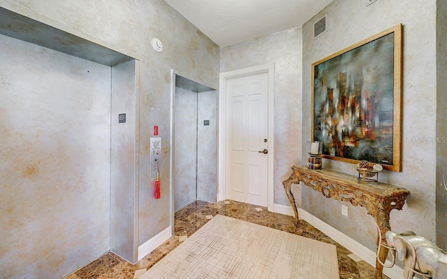 interior space with a textured ceiling and elevator