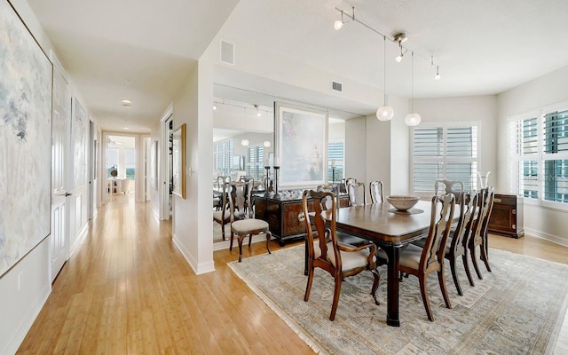 dining area featuring baseboards, visible vents, track lighting, and light wood finished floors