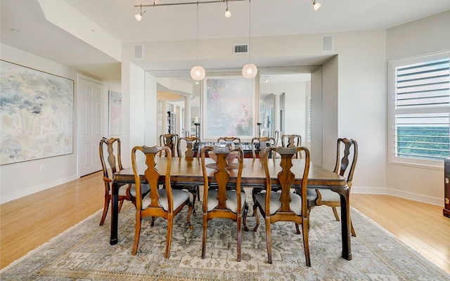 dining space with ornate columns, track lighting, and light hardwood / wood-style flooring