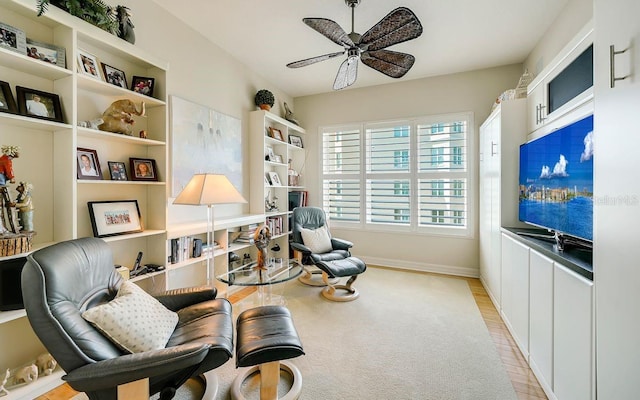 living area with baseboards and ceiling fan