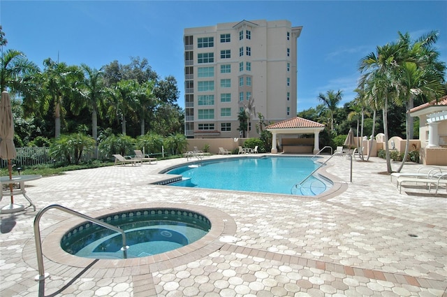 community pool featuring a hot tub, a gazebo, fence, and a patio area