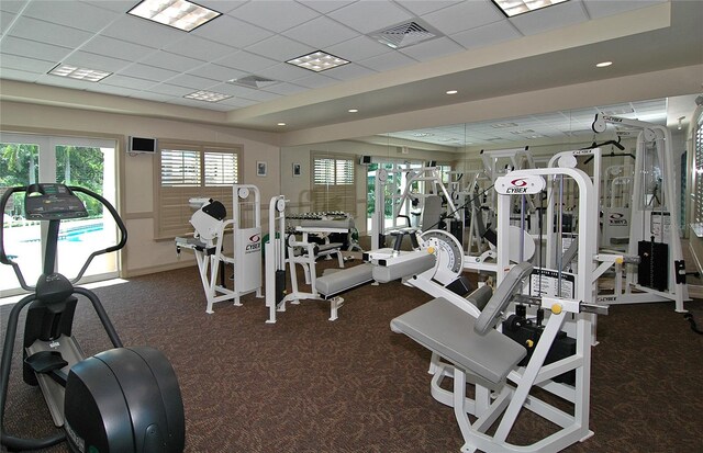 workout area with visible vents, a drop ceiling, and carpet