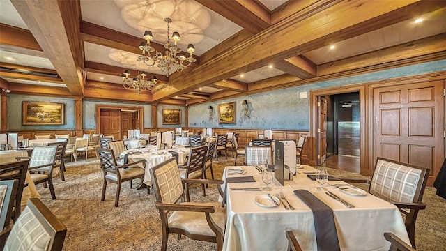 carpeted dining area with a decorative wall, beamed ceiling, coffered ceiling, and a chandelier
