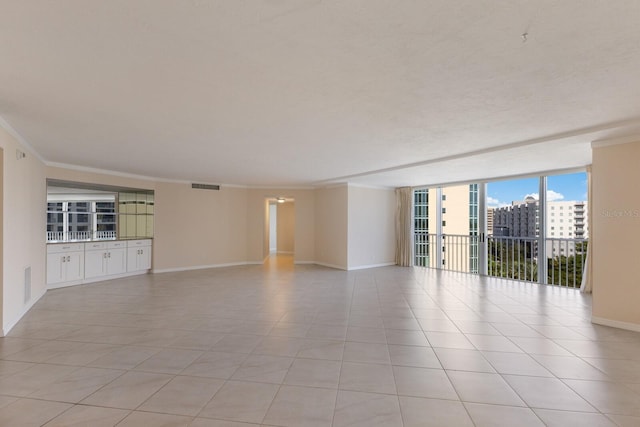 empty room featuring ornamental molding, light tile patterned floors, and floor to ceiling windows