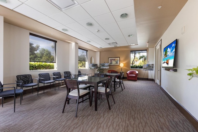 carpeted dining space featuring a drop ceiling