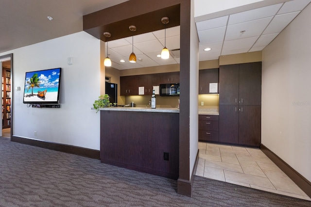 kitchen featuring light carpet, kitchen peninsula, dark brown cabinets, black refrigerator, and pendant lighting