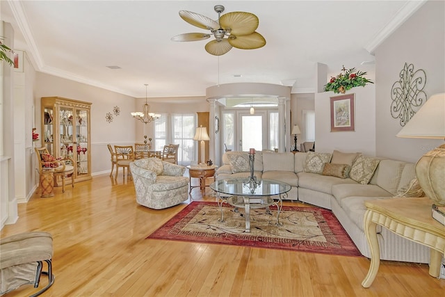 living room featuring ornate columns, crown molding, wood-type flooring, and ceiling fan with notable chandelier