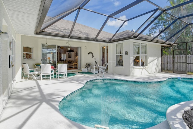 view of swimming pool featuring a patio, ceiling fan, and glass enclosure