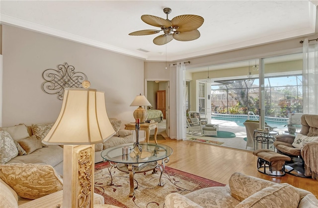 living room with crown molding, wood-type flooring, and ceiling fan