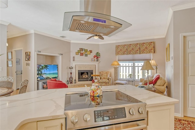 kitchen featuring light stone countertops, ornamental molding, cream cabinets, and stainless steel stove