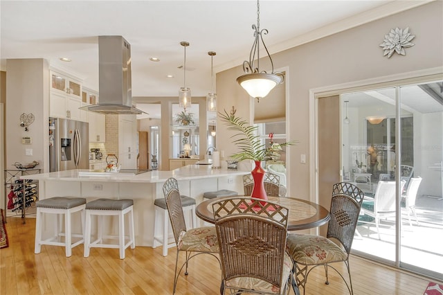 dining space with light hardwood / wood-style flooring and ornamental molding