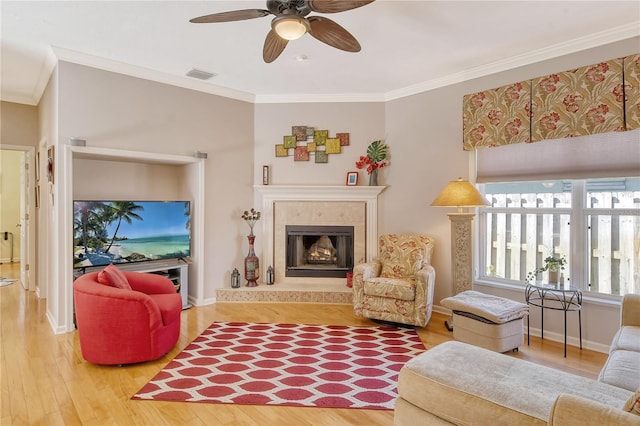 living room with a premium fireplace, hardwood / wood-style floors, ornamental molding, and ceiling fan