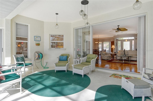 sitting room with concrete flooring and ceiling fan with notable chandelier