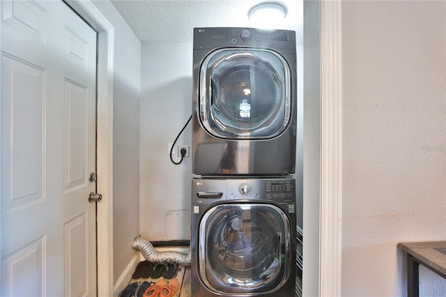 laundry area featuring a textured ceiling and stacked washing maching and dryer