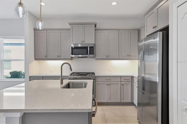 kitchen featuring hanging light fixtures, light stone countertops, appliances with stainless steel finishes, and gray cabinetry