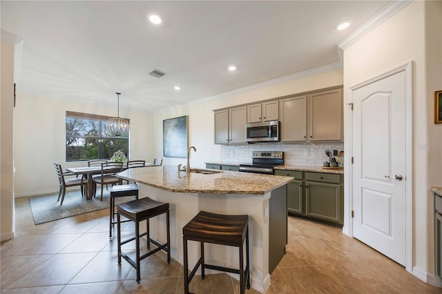 kitchen with a center island with sink, appliances with stainless steel finishes, sink, and decorative light fixtures