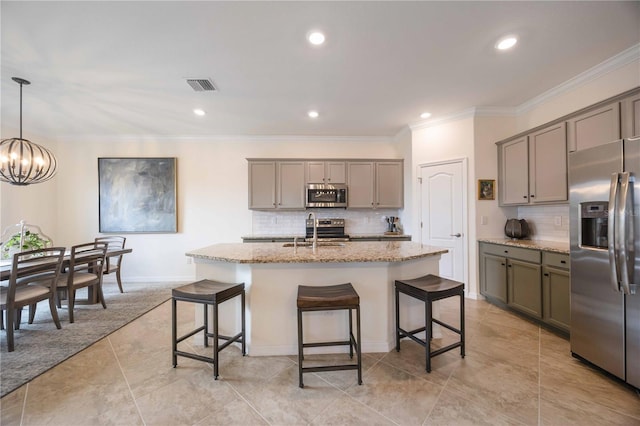 kitchen with stainless steel appliances, a center island with sink, sink, backsplash, and pendant lighting