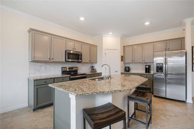 kitchen with stainless steel appliances, sink, a breakfast bar, light stone counters, and an island with sink