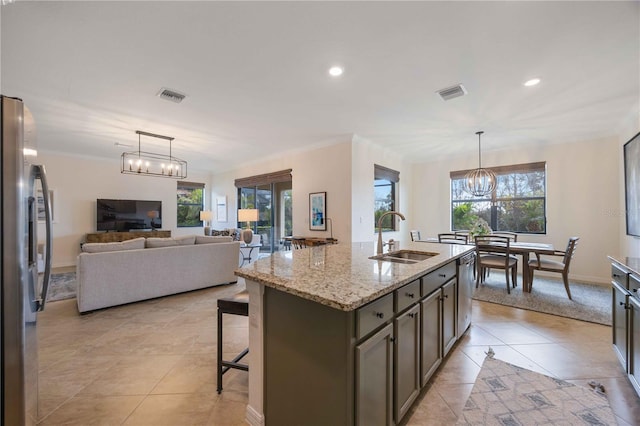 kitchen featuring a wealth of natural light, sink, an island with sink, and light stone countertops