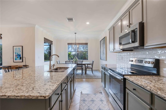 kitchen with stainless steel appliances, sink, light tile patterned floors, an island with sink, and pendant lighting