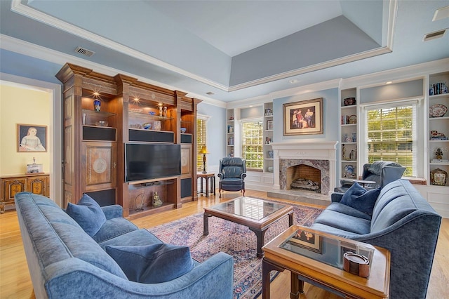 living room with a premium fireplace, hardwood / wood-style floors, a healthy amount of sunlight, and a raised ceiling