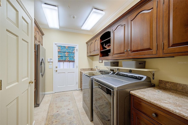 clothes washing area featuring ornamental molding, independent washer and dryer, light tile patterned floors, and cabinets