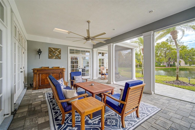 sunroom / solarium with a water view, ceiling fan, decorative columns, and french doors