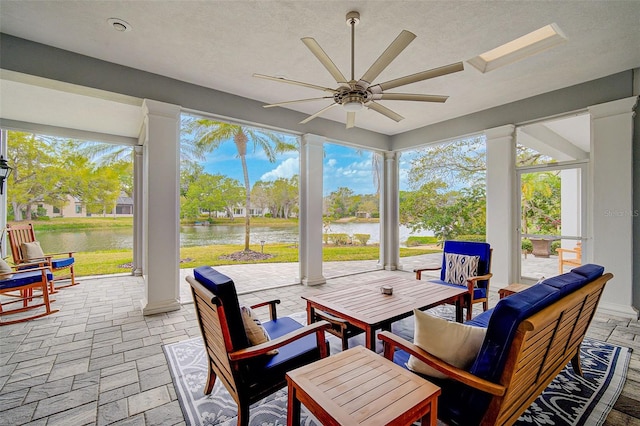 sunroom with plenty of natural light, a water view, and ceiling fan