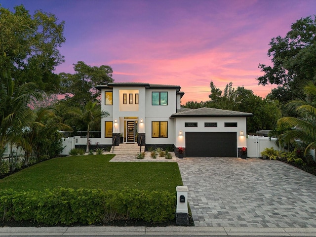 view of front of home with a garage and a lawn