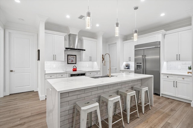 577 Venice Ln, Sarasota, FL 34242 - kitchen with stainless steel built in fridge, a sink, wall chimney range hood, a center island with sink, and tasteful backsplash