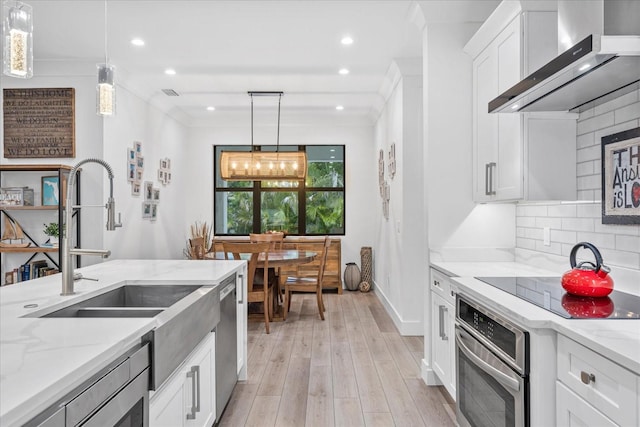 577 Venice Ln, Sarasota, FL 34242 - kitchen with stainless steel appliances, wall chimney exhaust hood, a sink, light stone countertops, and light wood-style flooring