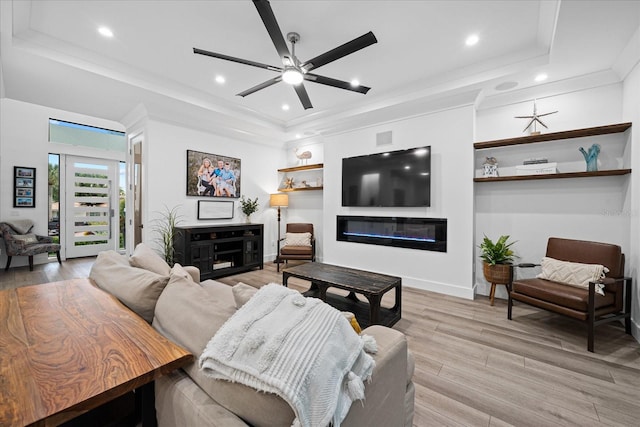 living room featuring ornamental molding, ceiling fan, light hardwood / wood-style floors, and a tray ceiling