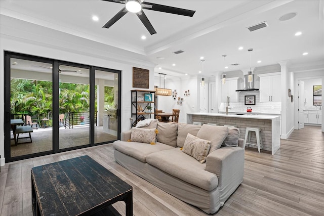 living room with ceiling fan, light hardwood / wood-style floors, crown molding, and sink