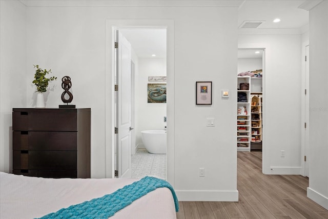 bedroom featuring a walk in closet, light hardwood / wood-style floors, and ensuite bathroom