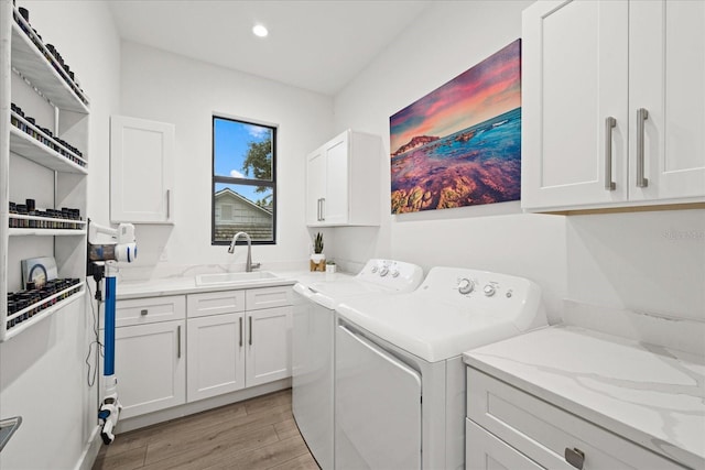 laundry area with sink, cabinets, light hardwood / wood-style floors, and separate washer and dryer