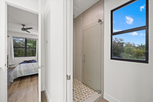 bathroom with ceiling fan, a shower with door, and hardwood / wood-style floors