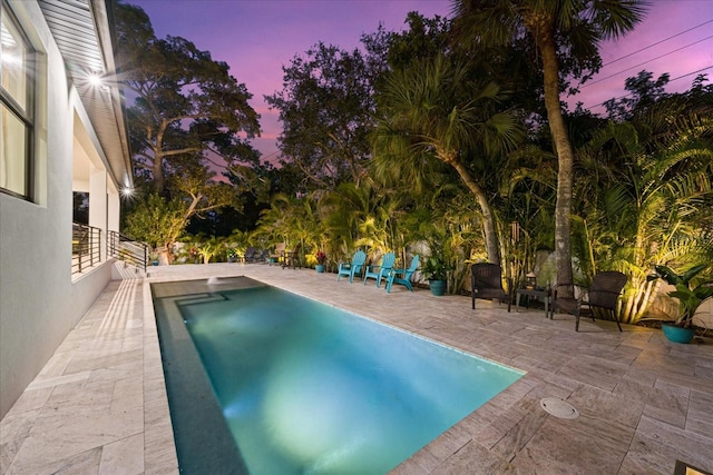 pool at dusk with a patio area