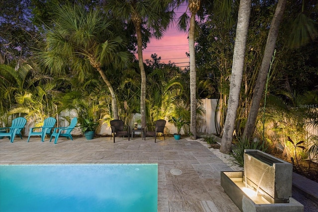 pool at dusk featuring a patio