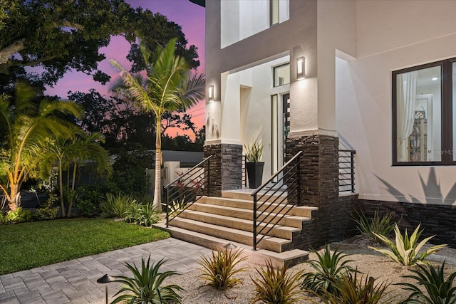 577 Venice Ln, Sarasota, FL 34242 - property entrance with stucco siding, stone siding, and a lawn