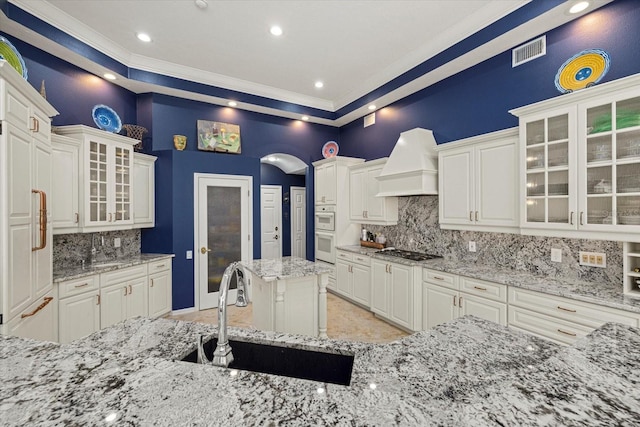 kitchen with sink, white cabinetry, stainless steel gas cooktop, and custom range hood