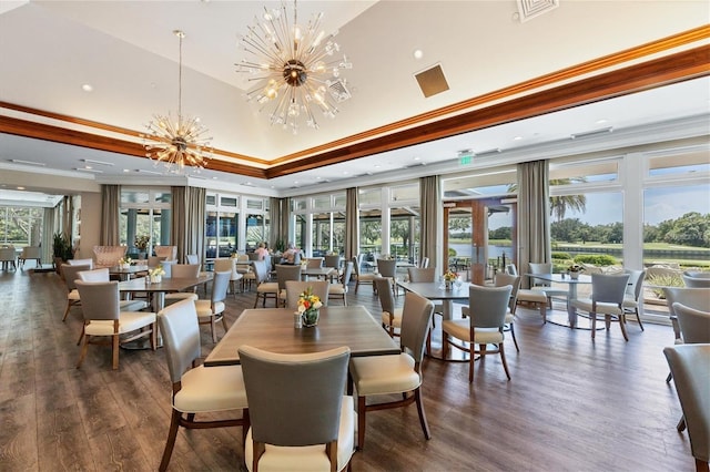 dining space with dark wood-type flooring, a chandelier, a tray ceiling, and ornamental molding