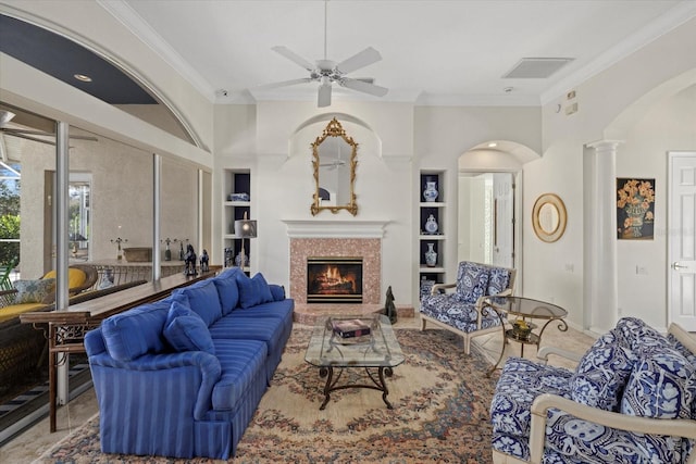 living room with built in shelves, ornamental molding, ceiling fan, and decorative columns