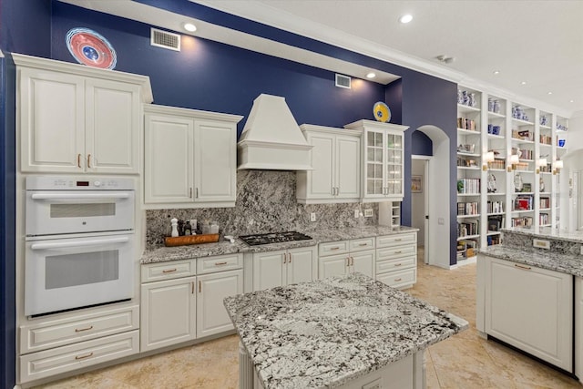 kitchen featuring white cabinetry, white double oven, crown molding, and light stone countertops