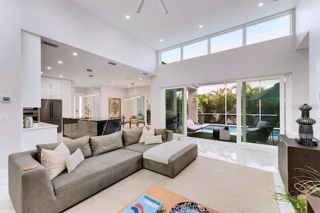 living room with a towering ceiling, sink, and plenty of natural light