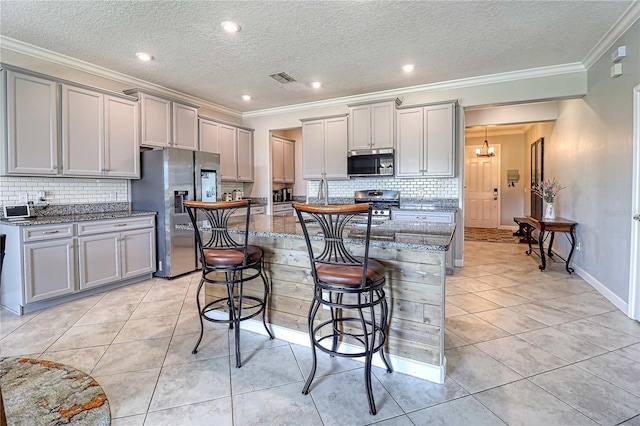 kitchen featuring stainless steel appliances, gray cabinets, light tile patterned flooring, and a kitchen breakfast bar