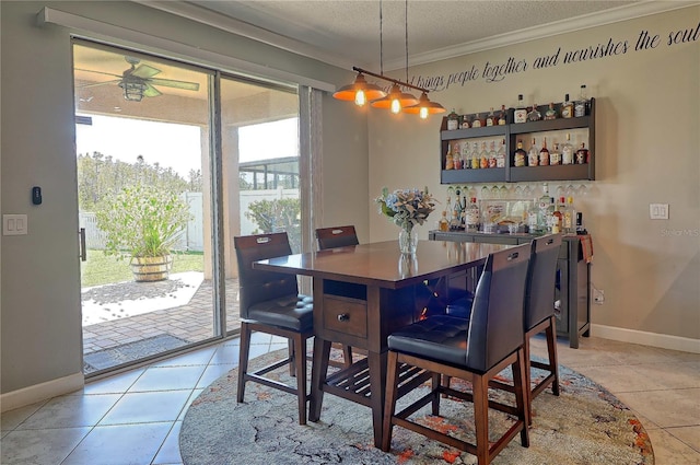 dining room with light tile patterned floors, ornamental molding, a textured ceiling, and baseboards